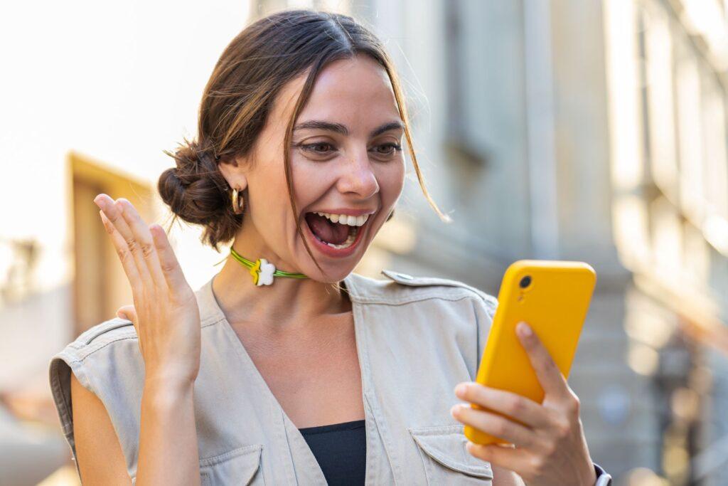 Frau freut sich über etwas auf ihrem Smartphone