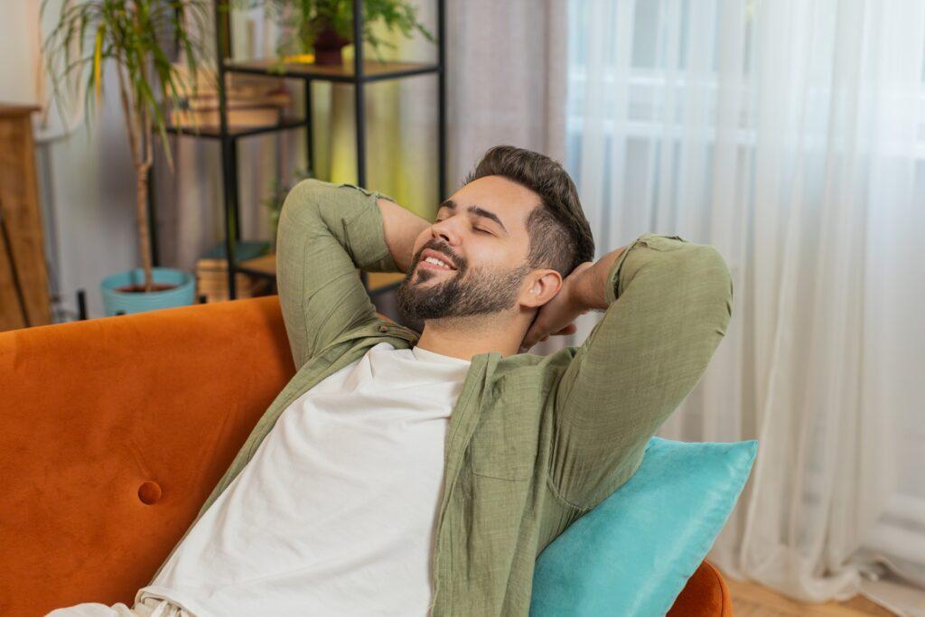 Mann entspannt auf Sofa im Wohnzimmer | Duschrückwand