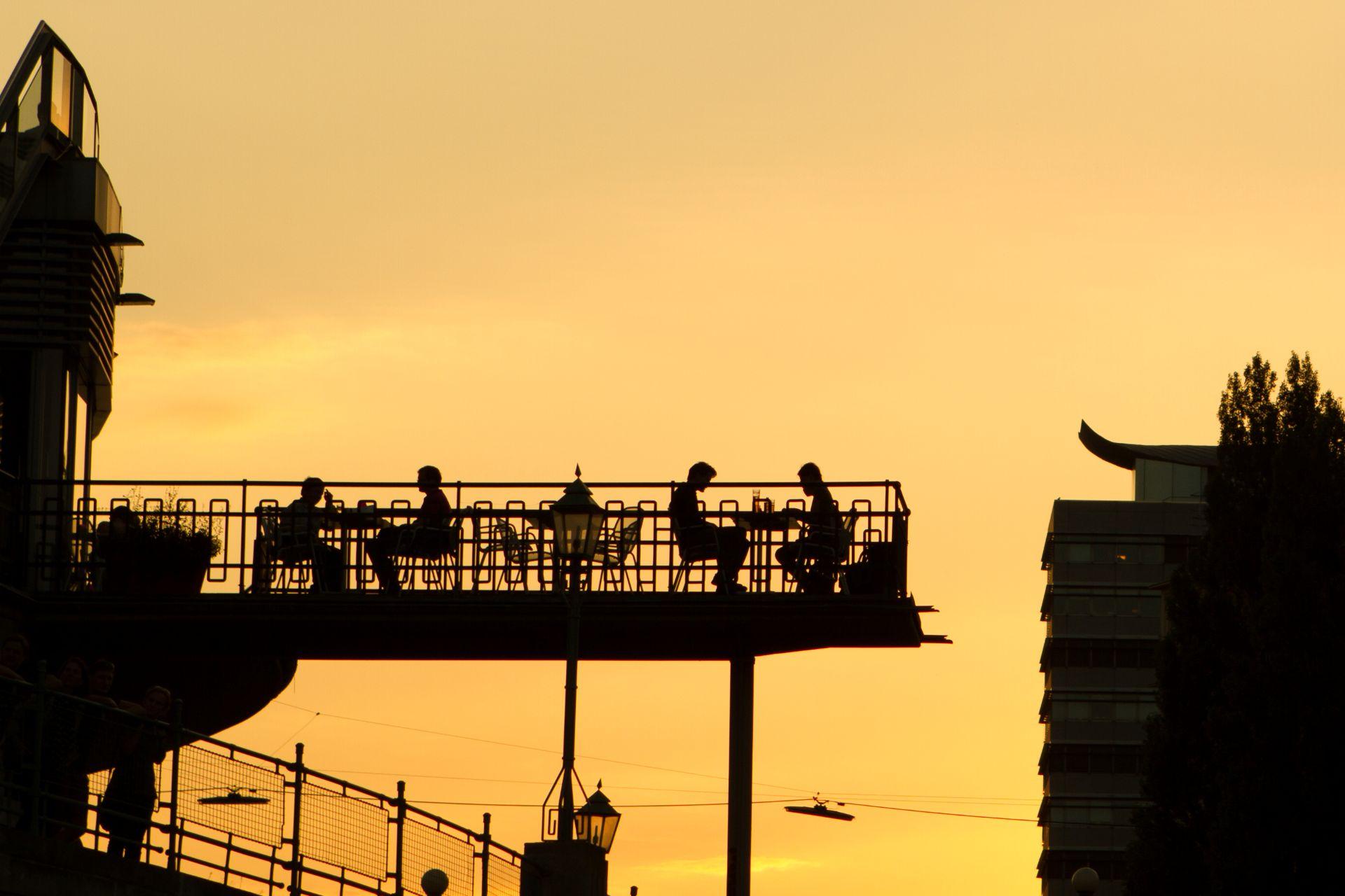 silhouetten von menschen in einer rooftop-bar in wien bei sonnenuntergang