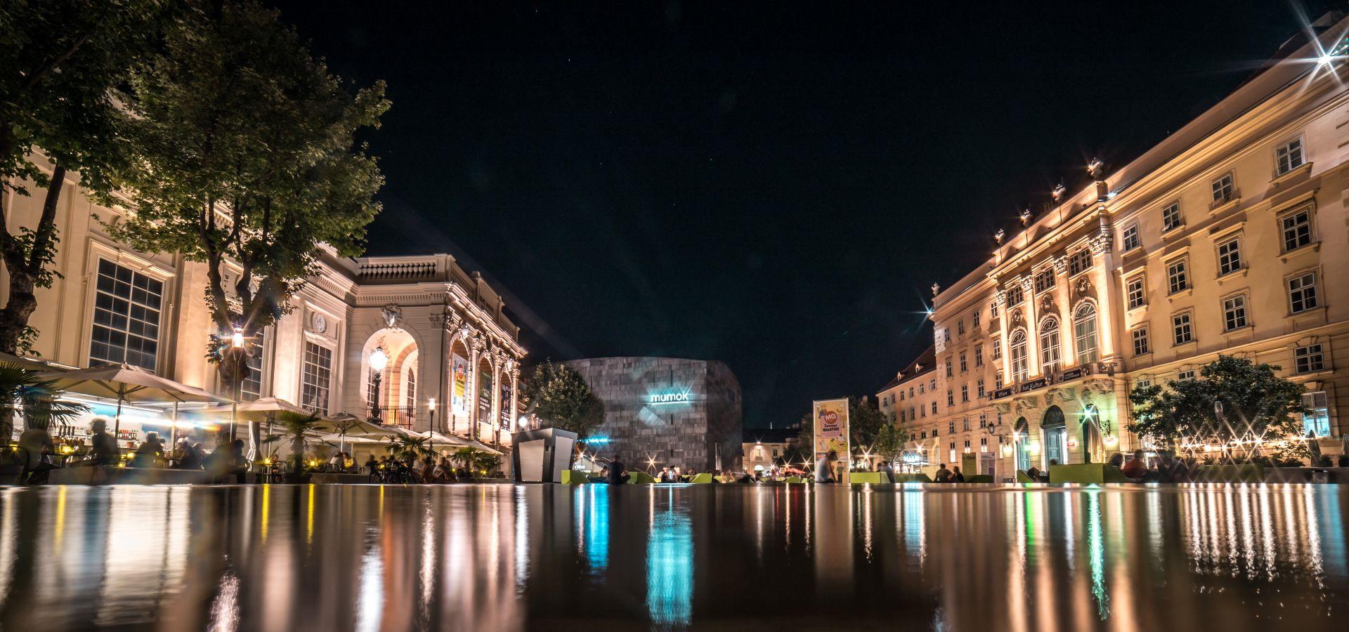 beleuchtetes museumsquartier wien mit lichtreflexionen im wasser
