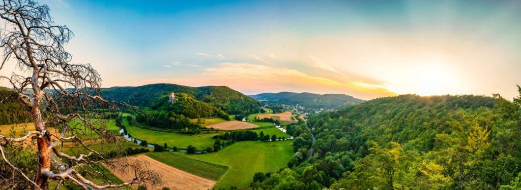 Panoramablick auf die Fraenkische Schweiz mit Flusstal, Wiesen und Burg im Abendlicht, Sinnbild fuer Ruhe und Gelassenheit
